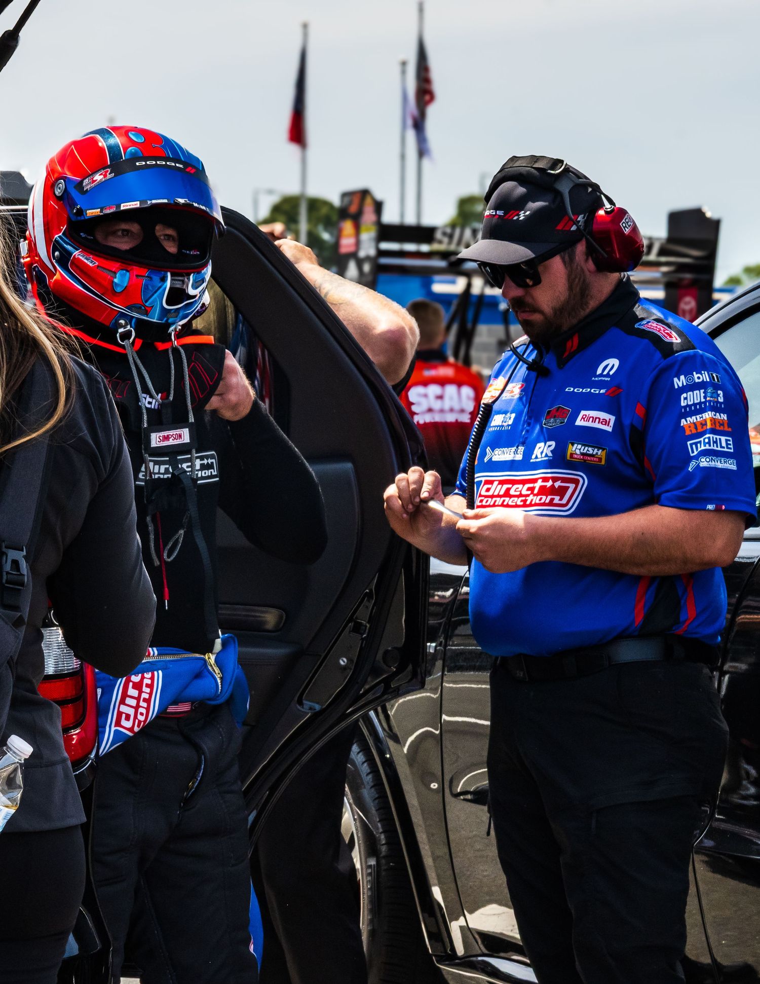 Pit crew members in blue and black uniforms working on race car adjustments.