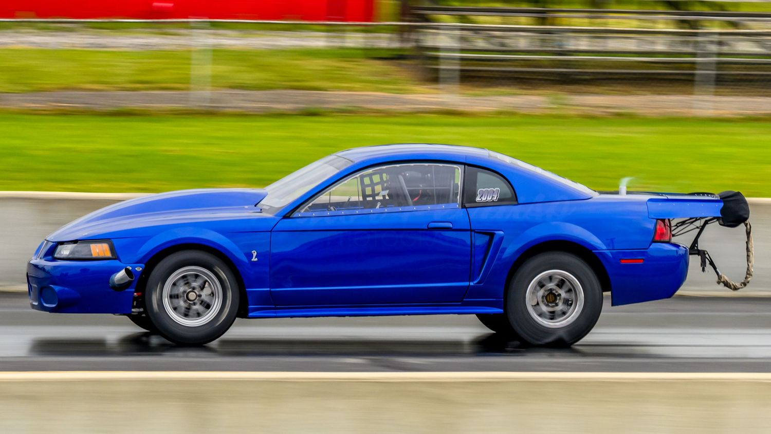 A row of classic blue Ford Mustangs lined up at a car show displaying various model years and styles.