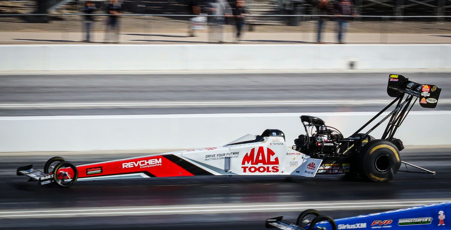 Colorful drag racing cars competing in a professional racing event.
