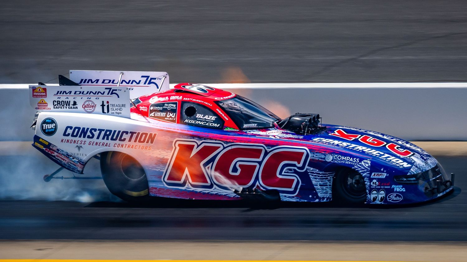 Professional drag racing cars with sponsor graphics racing down the track.