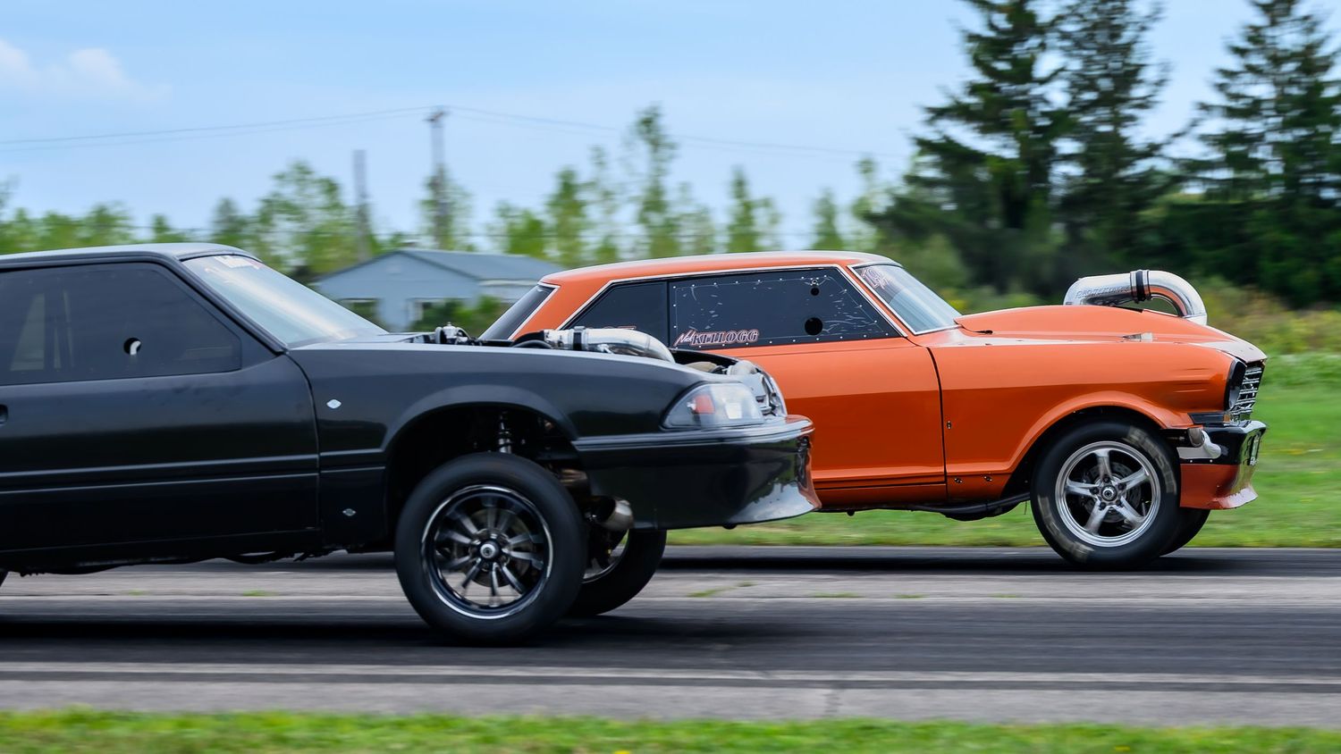 Multiple classic cars competing in drag races with tire smoke visible.