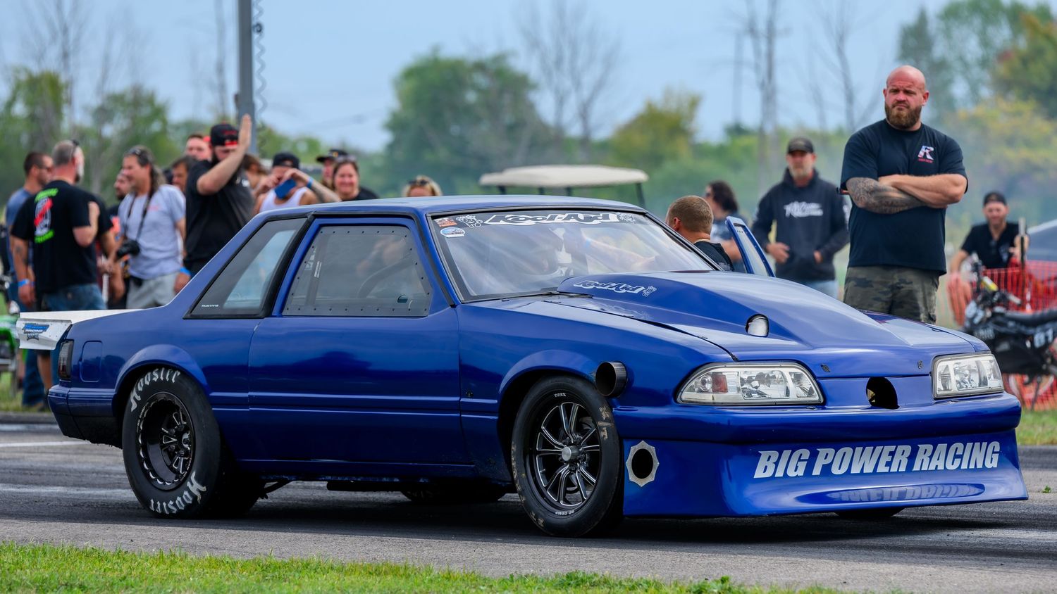 Blue and black modified race cars competing at a drag racing event.