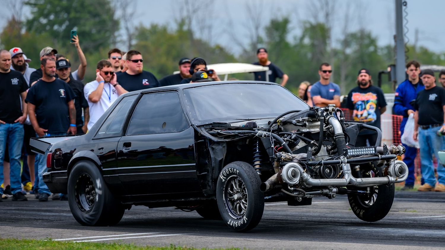 Performance vehicles line up for drag racing competition at a motorsports track.