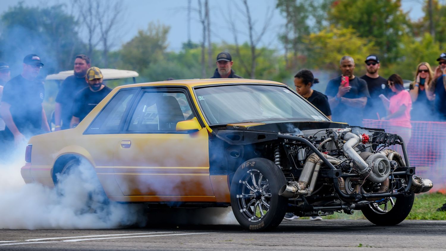Drag racing cars creating smoke and burnouts during a racing competition.