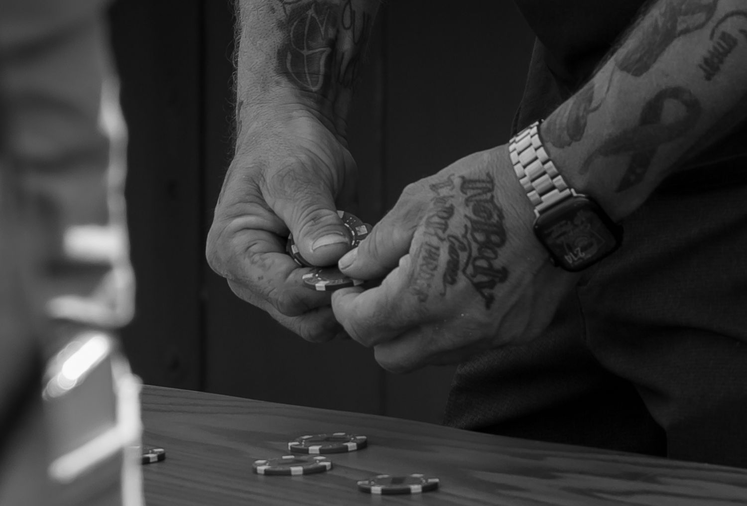 Close-up black and white shot of hands rolling dice on a dark surface.