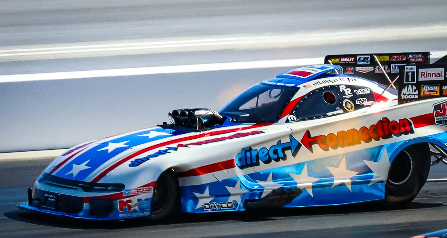 Patriotic themed drag racing cars speeding down the race track.