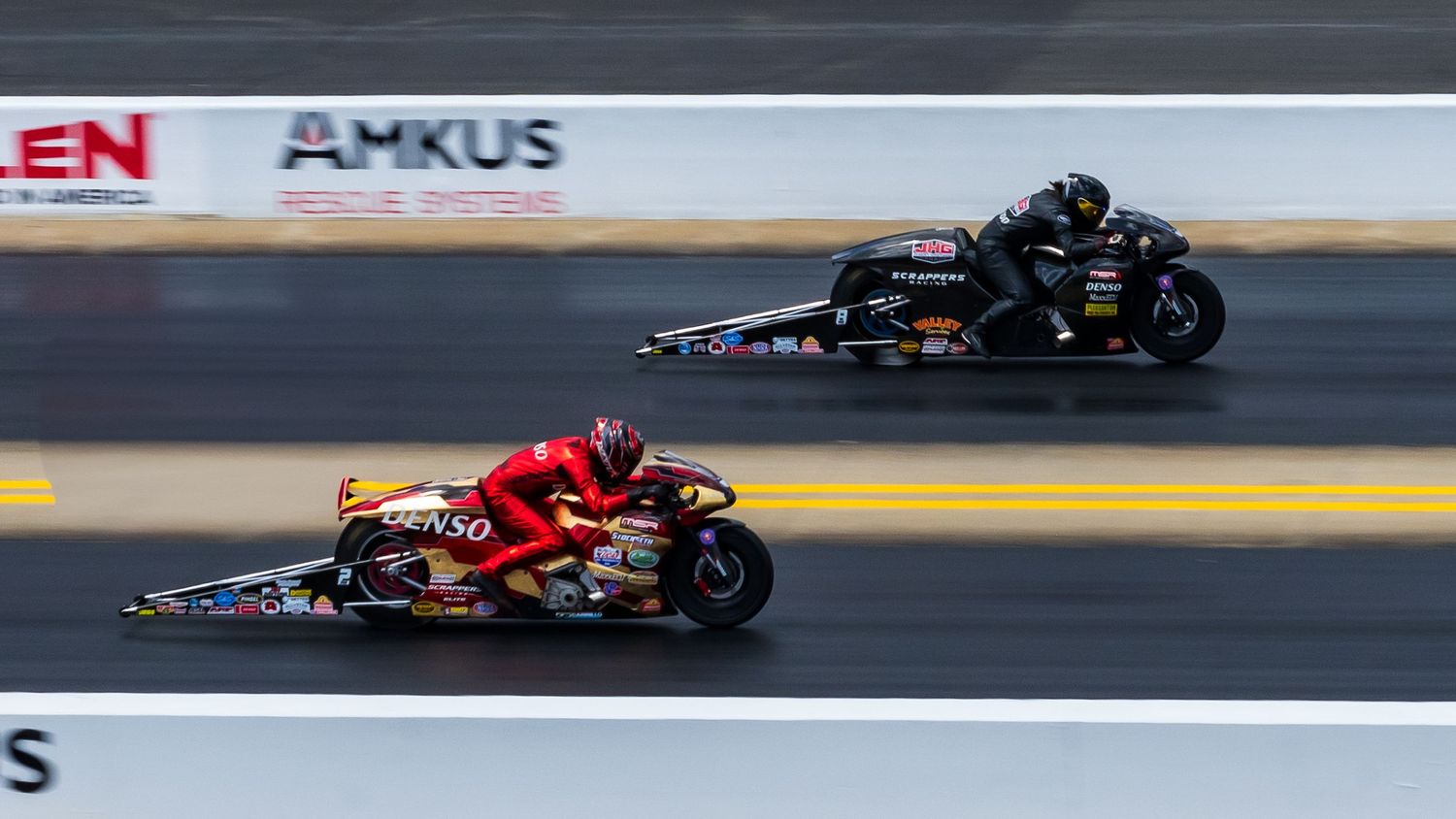 Motorcycles and drag racing vehicles competing on a professional racing strip.