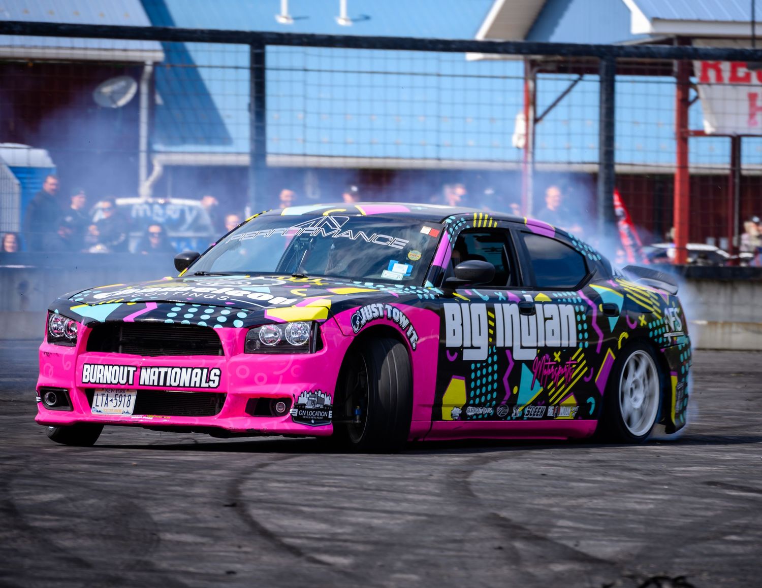 Colorful pink and black drift car with Big Mudah wrap performing burnout at Burnout Nationals event.