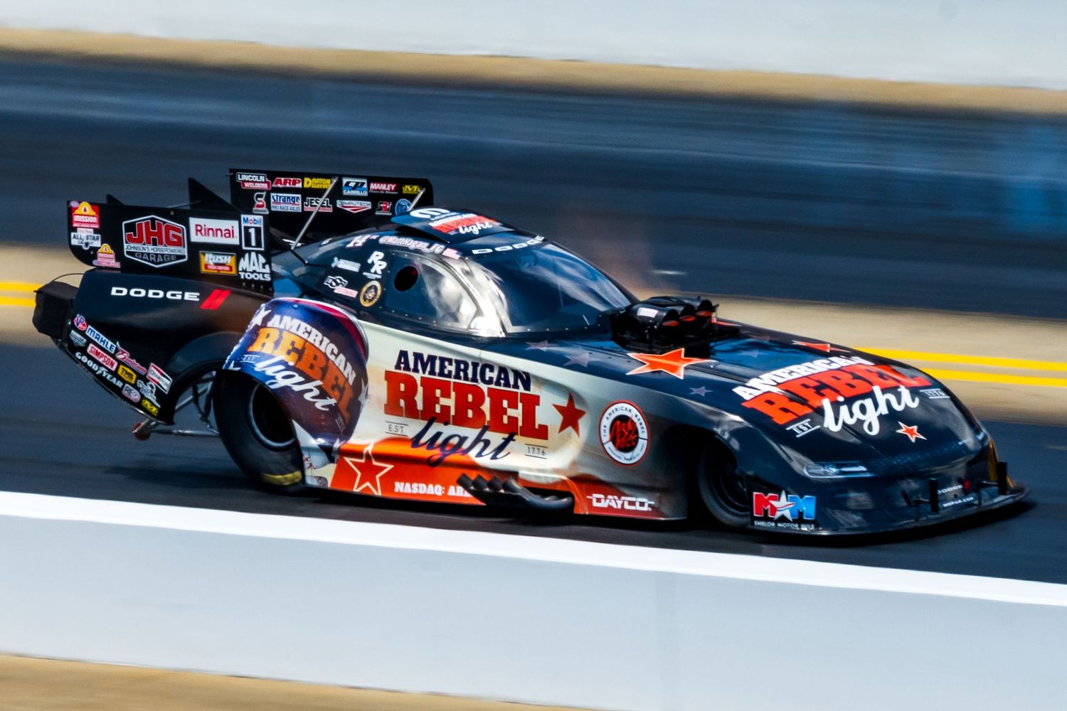 High-speed drag racing cars competing on a professional racetrack with colorful sponsorship liveries.