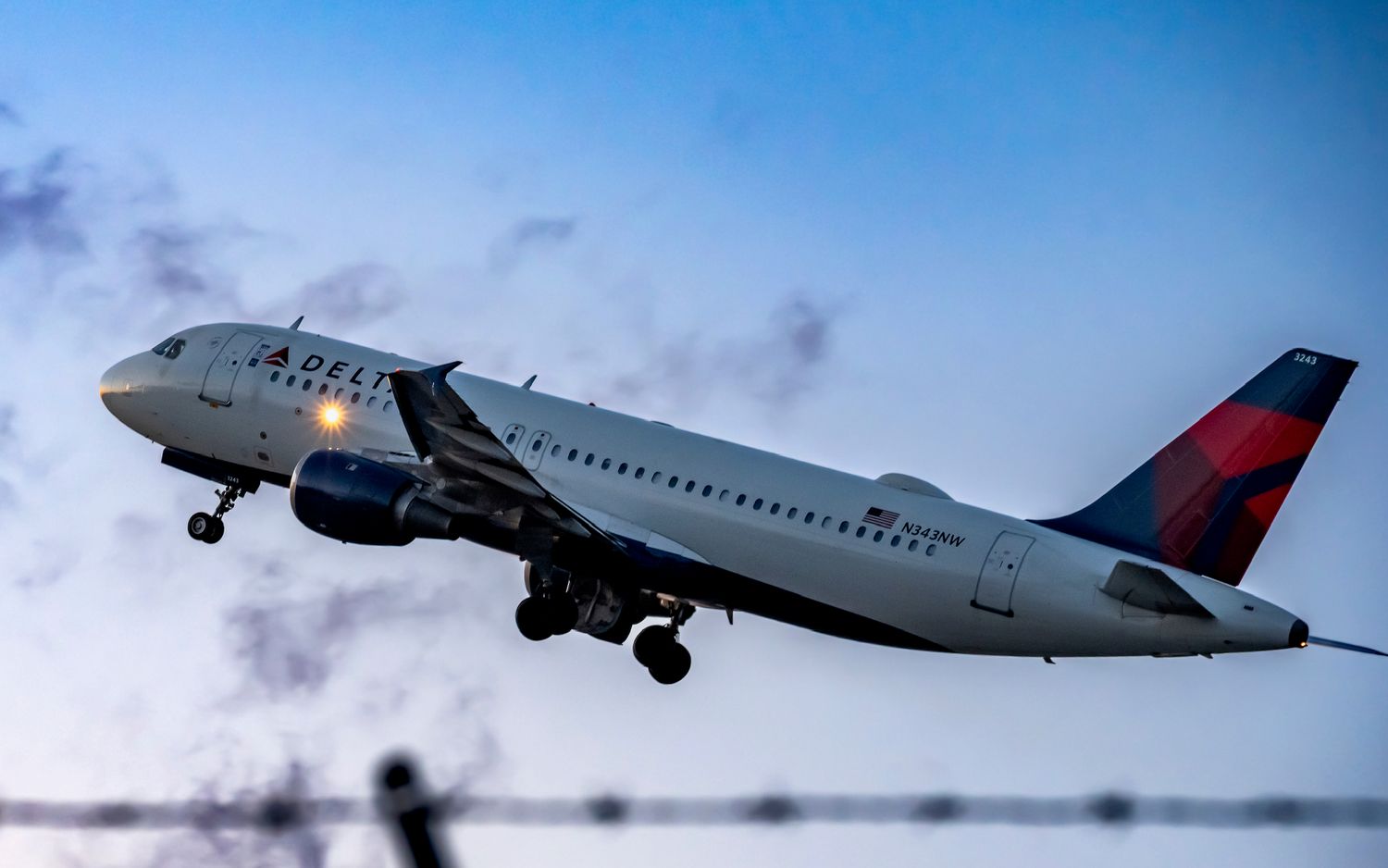 Delta Air Lines Airbus A320 aircraft taking off against a dramatic dusk sky.