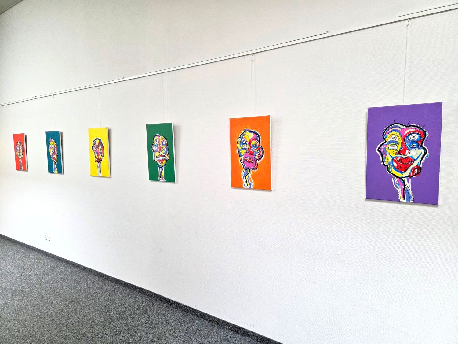Colorful abstract portrait paintings from Zailou displayed on a white gallery wall in a modern exhibition space.