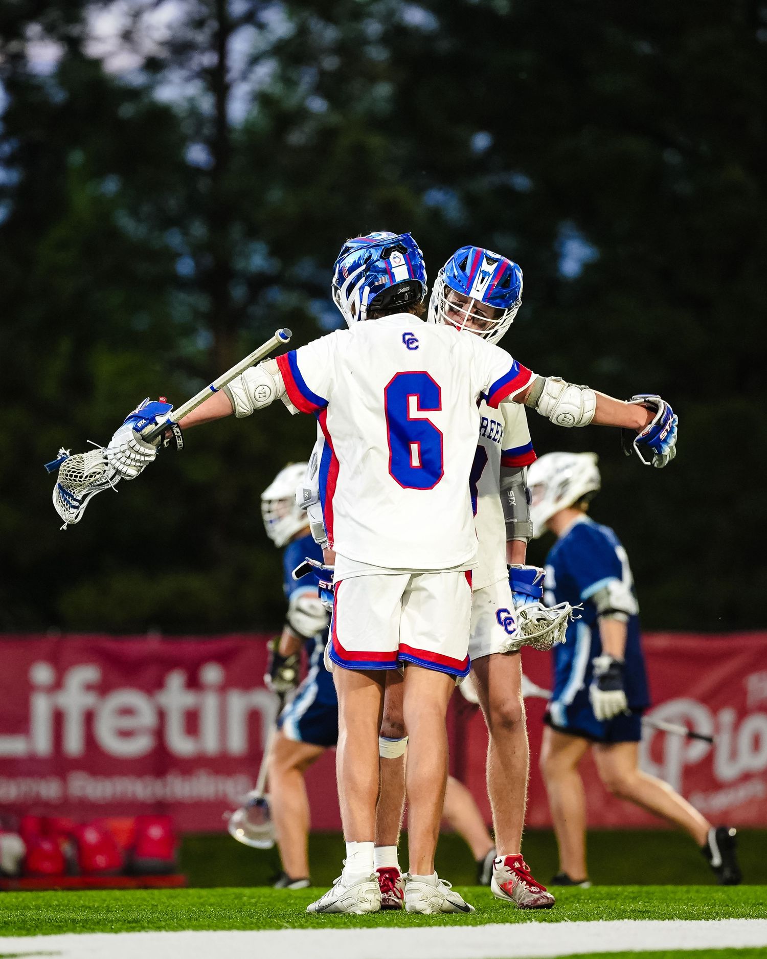 Lacrosse players celebrate by bumping chests.