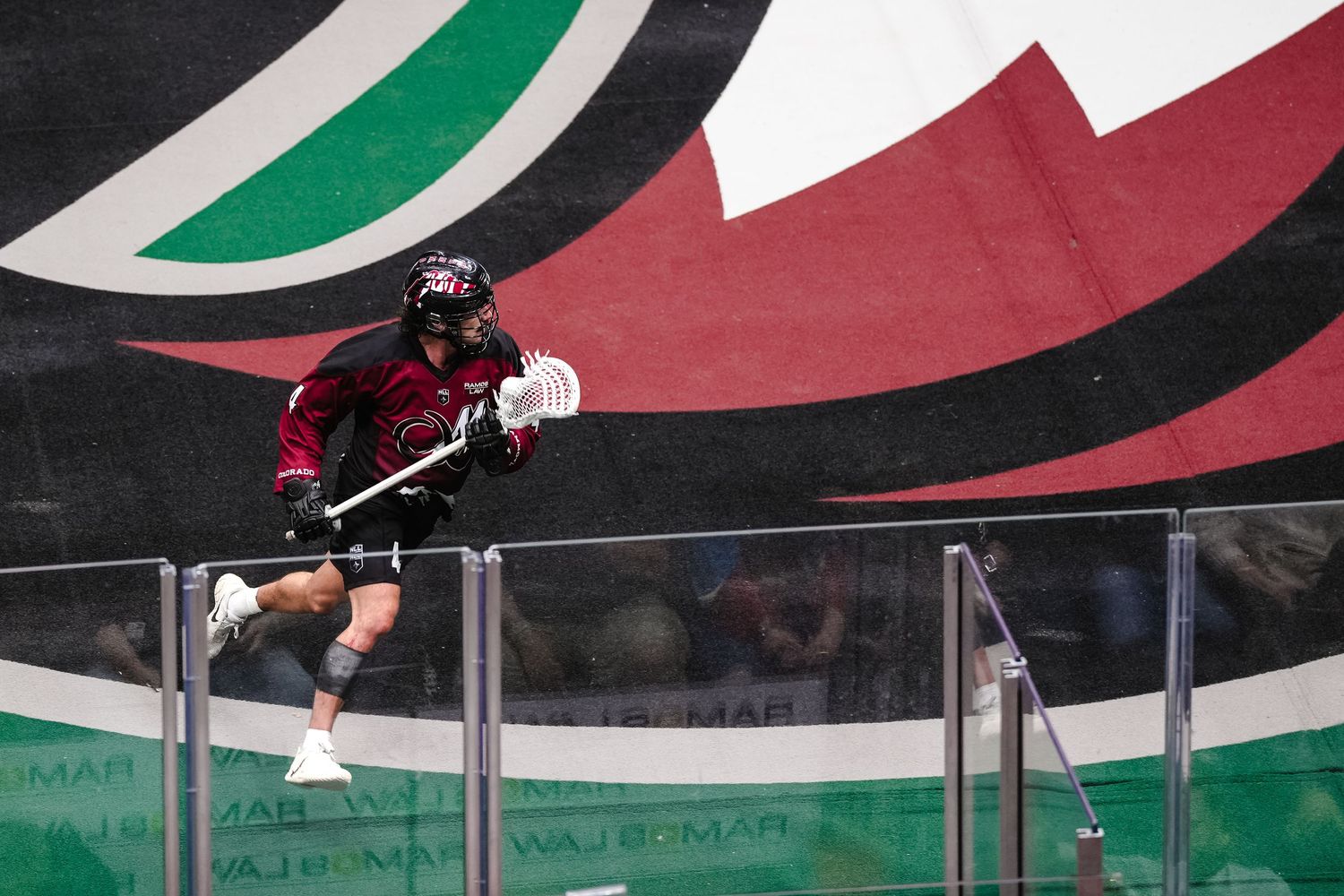 Professional lacrosse player in action on an indoor field.