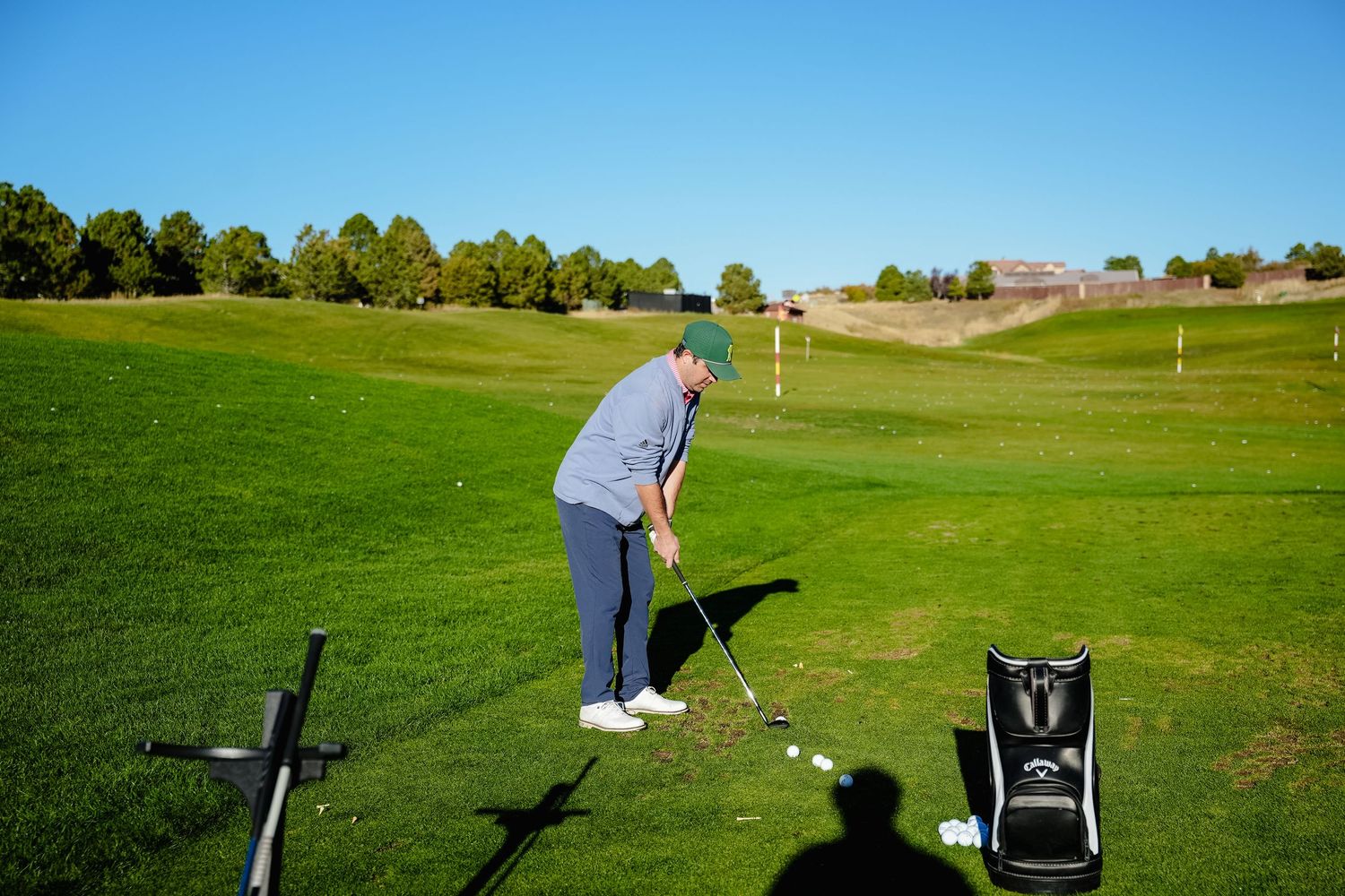 Golf course landscape with practice equipment and sunny blue skies.
