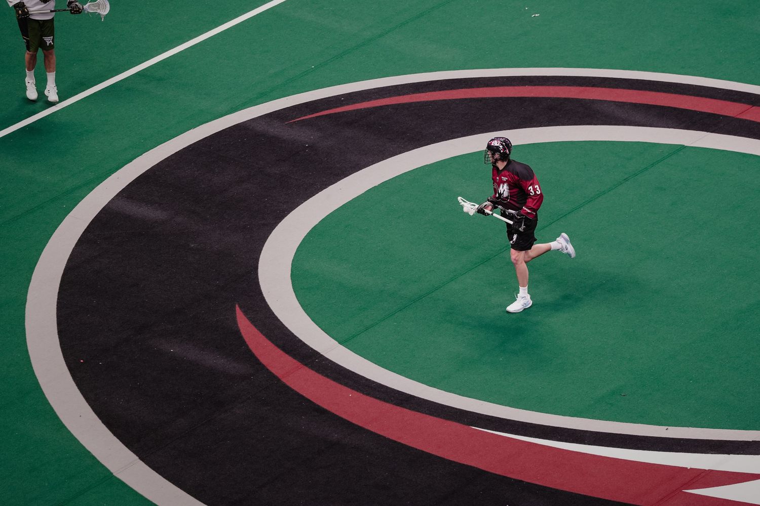 Lacrosse player runs across the field.