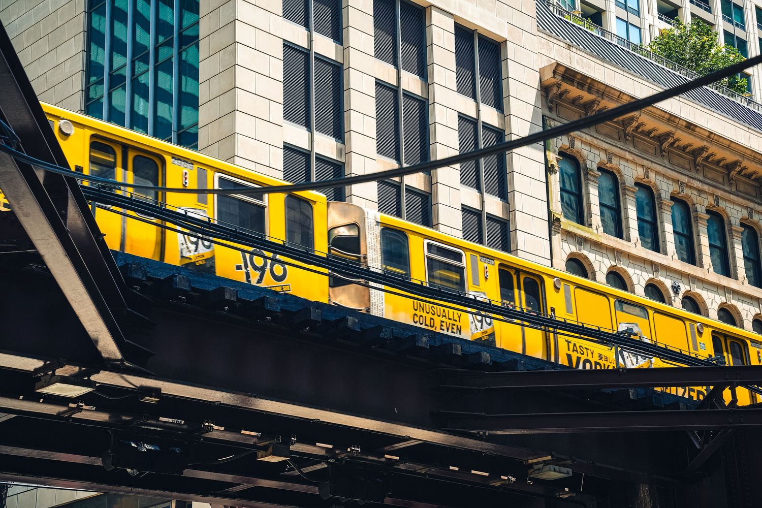 Yellow elevated train track against urban buildings in downtown setting.