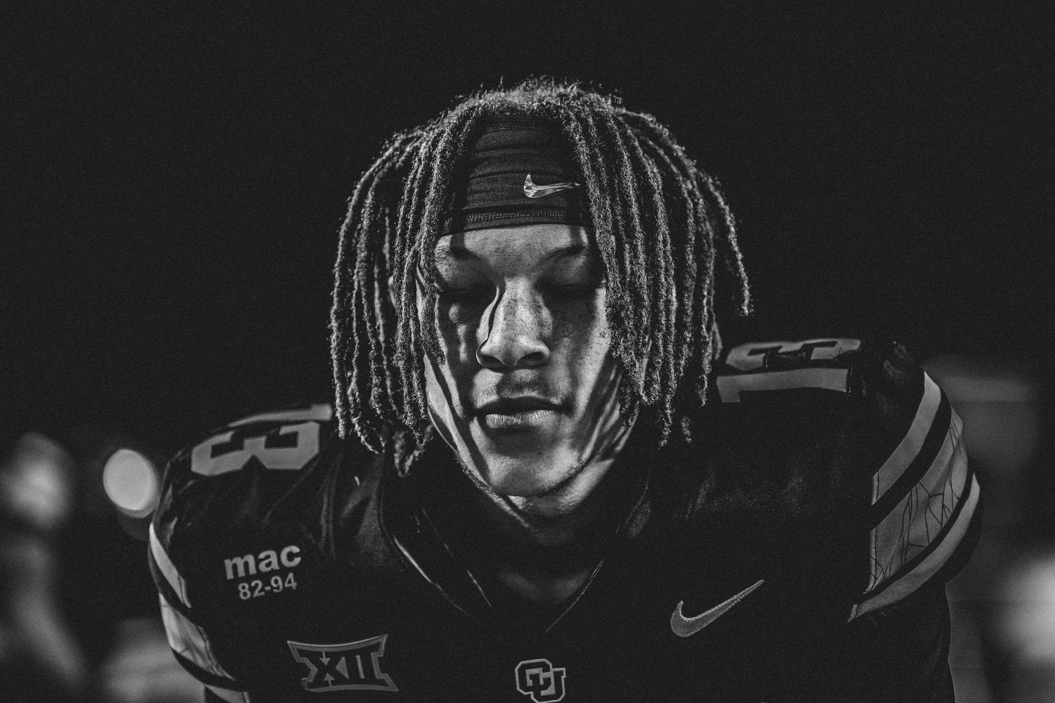 Dramatic black and white close-up portrait of football players with dreadlocks.