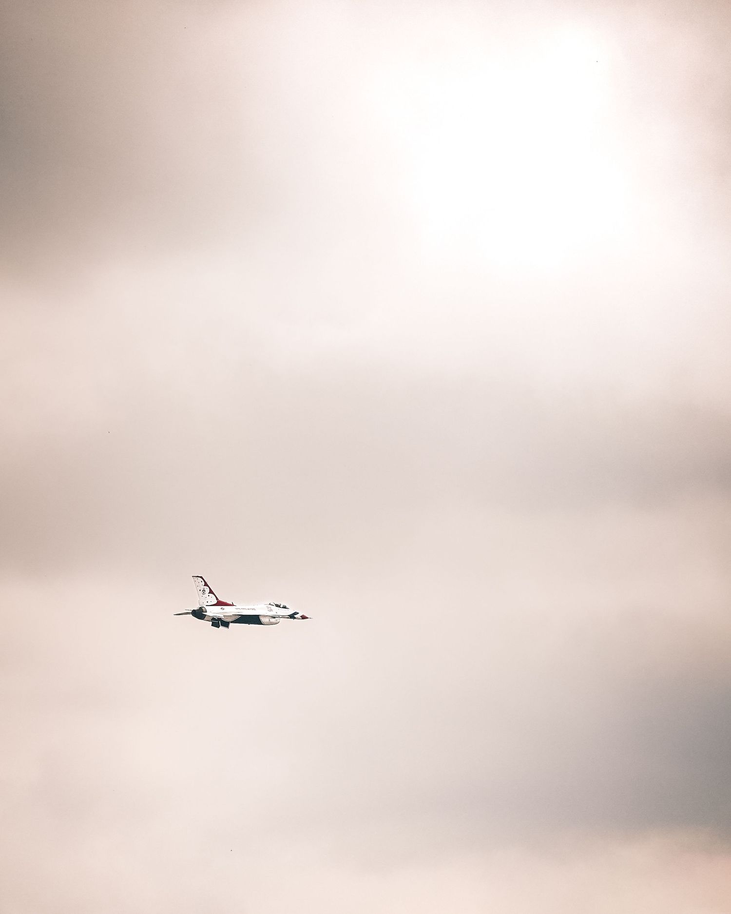Aircraft silhouette flying through overcast sky conditions.