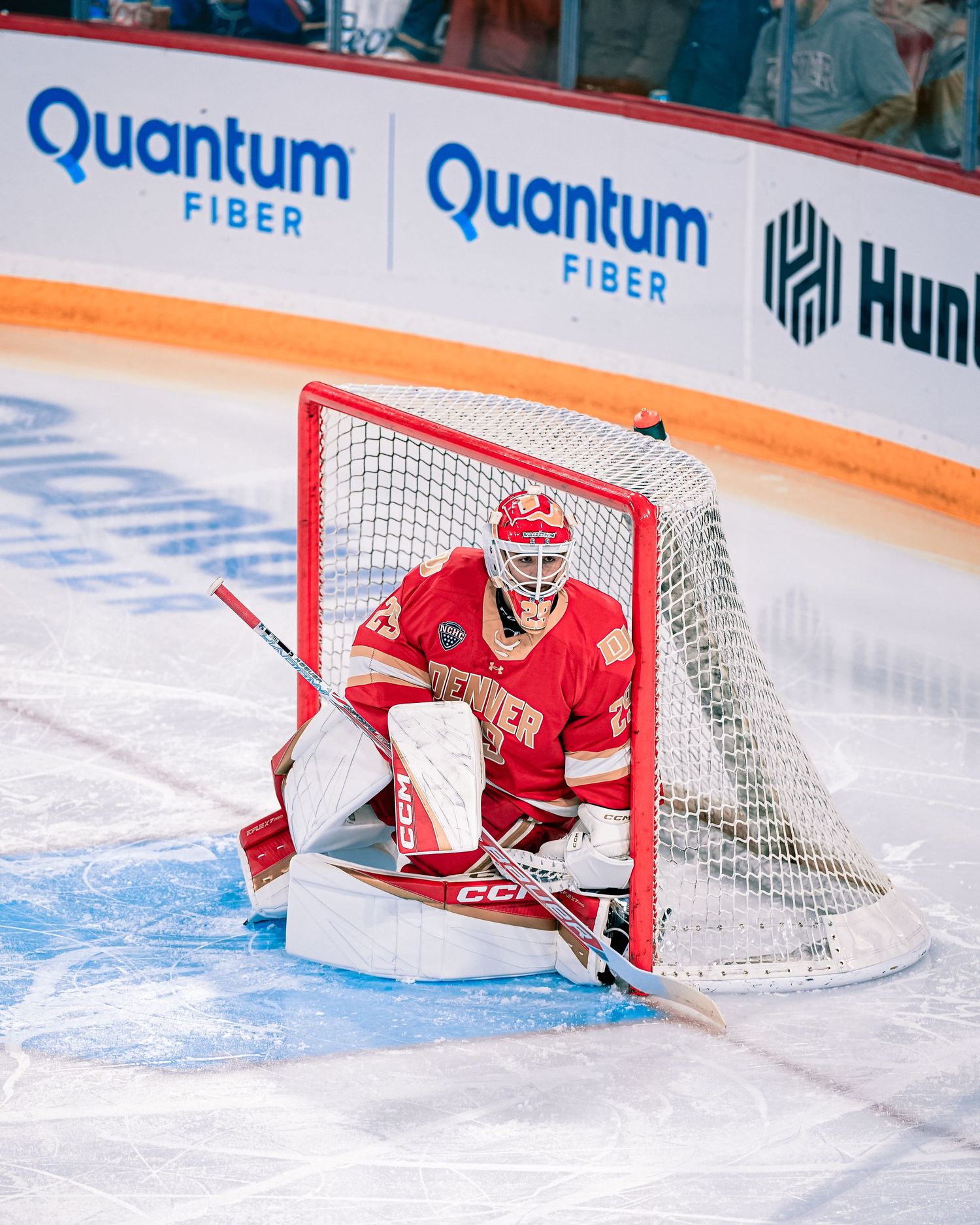 Hockey goalie in red uniform defends the net during a game.