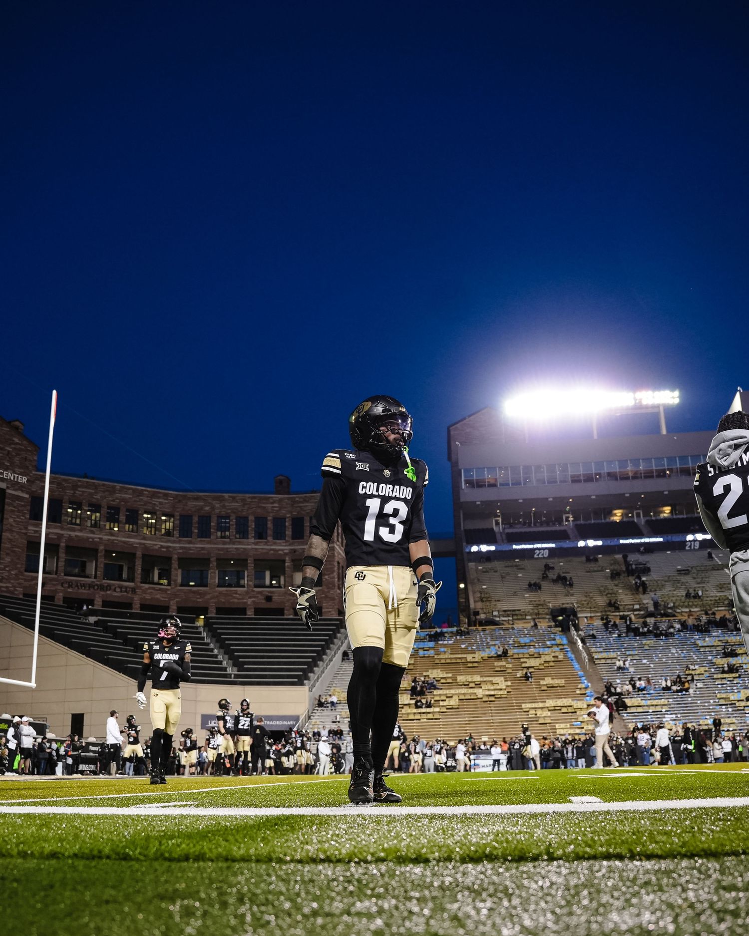 Football player warm up on a brightly lit field at night under stadium lights.
