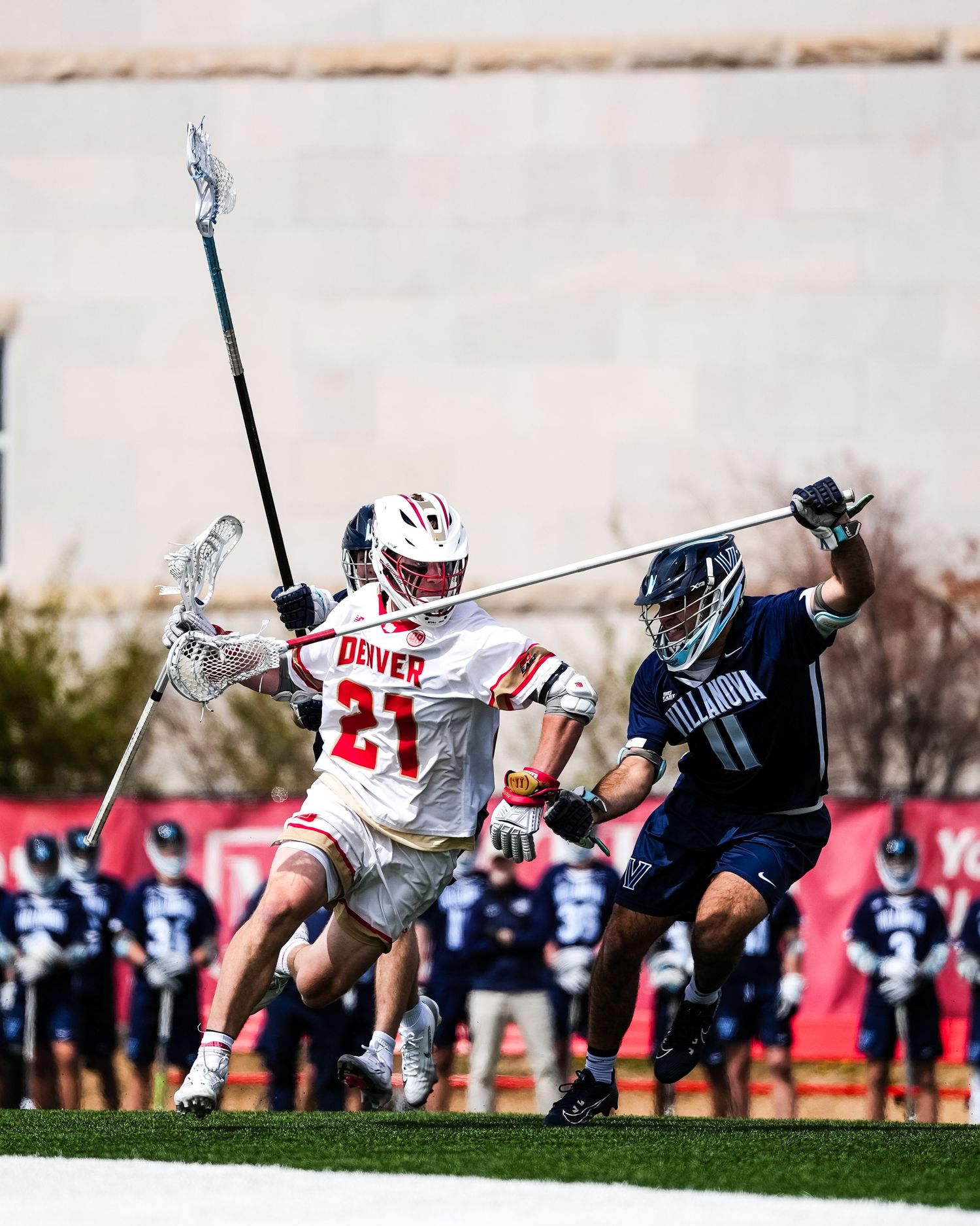 Lacrosse players collide mid-air during an intense game moment on the field.
