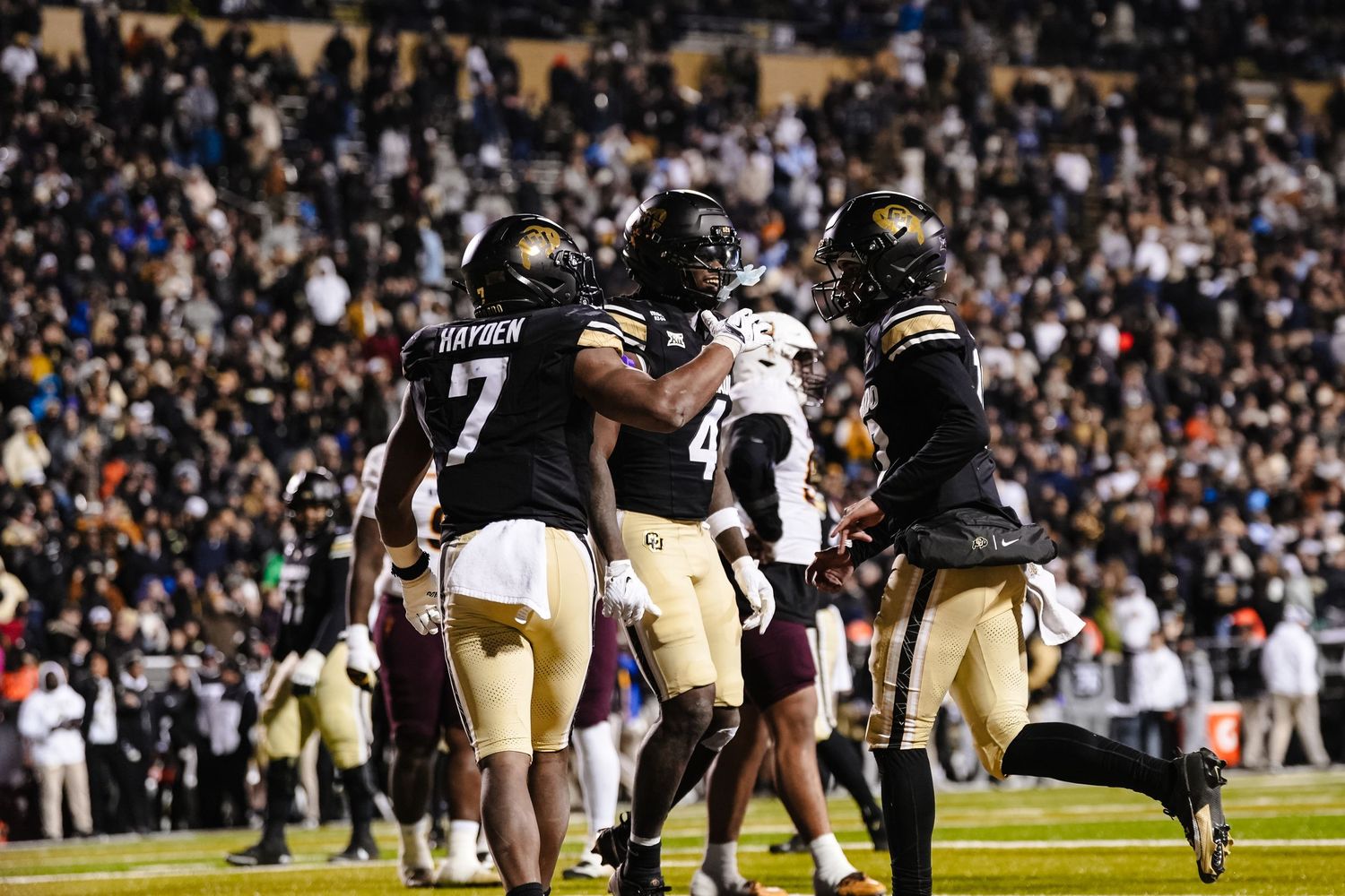 Football players lined up for play during night game with packed stadium crowd.