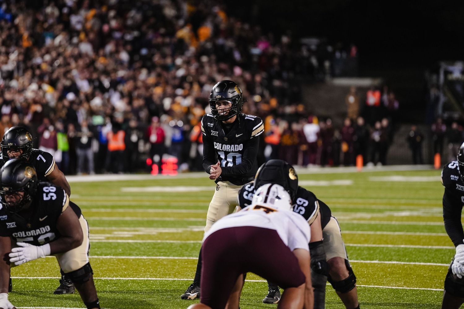 Football players in action during intense gameplay at night stadium.