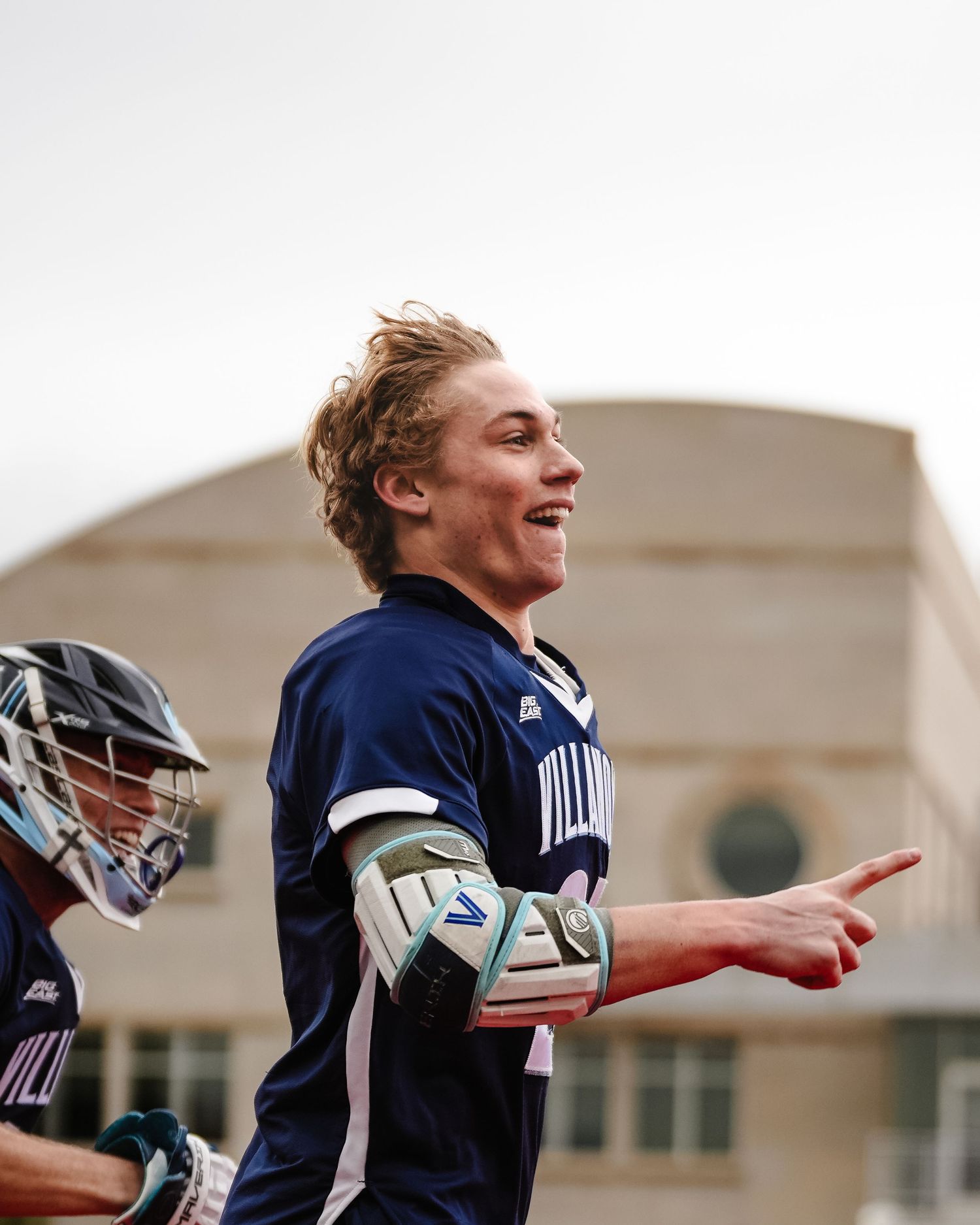 Player in navy uniform celebrating during a lacrosse game.