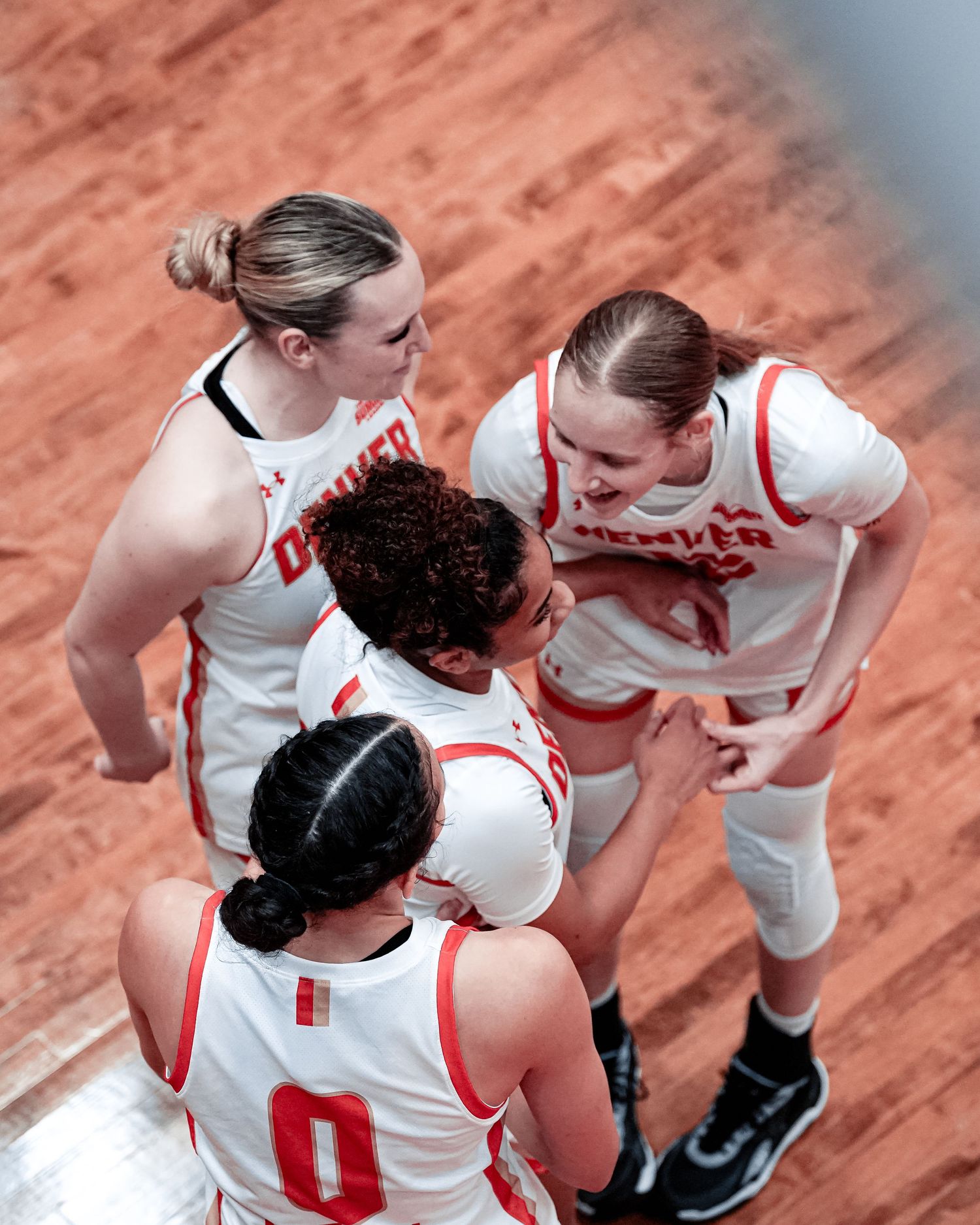 Denver basketball team players huddle together to celebrate.