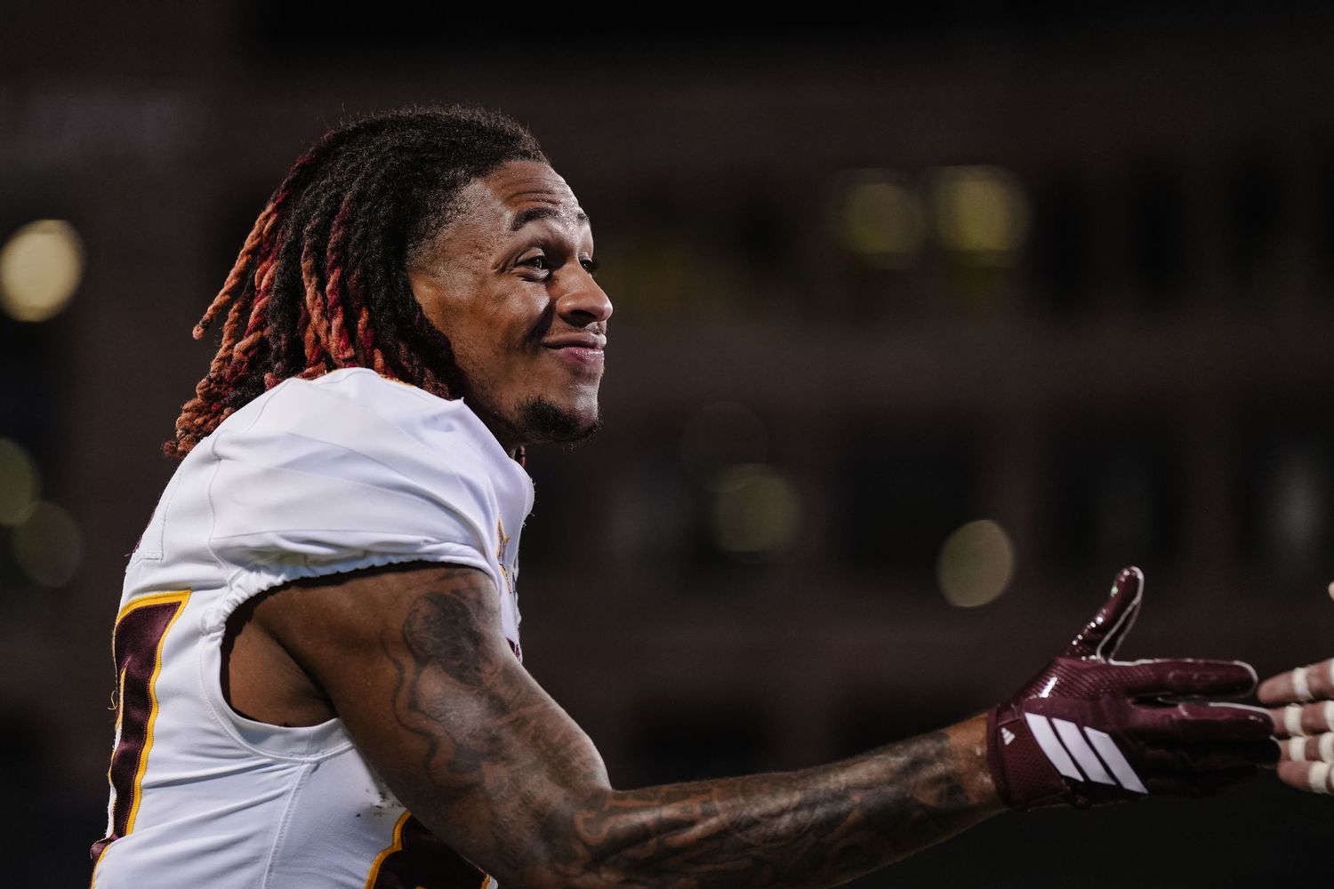 Football players celebrate on the field during a night game.