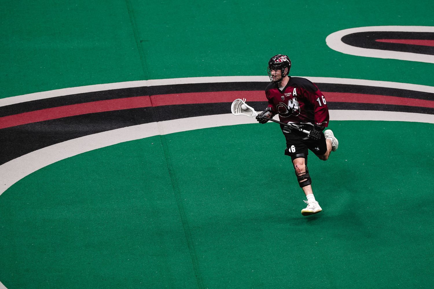 Lacrosse player runs across the field.