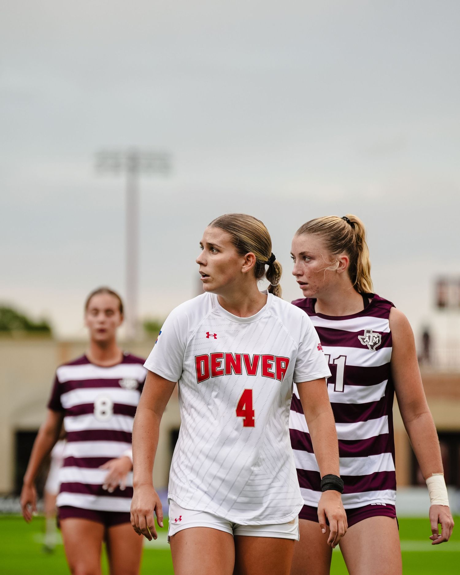 Soccer players in white and striped uniforms walking on field during a match.
