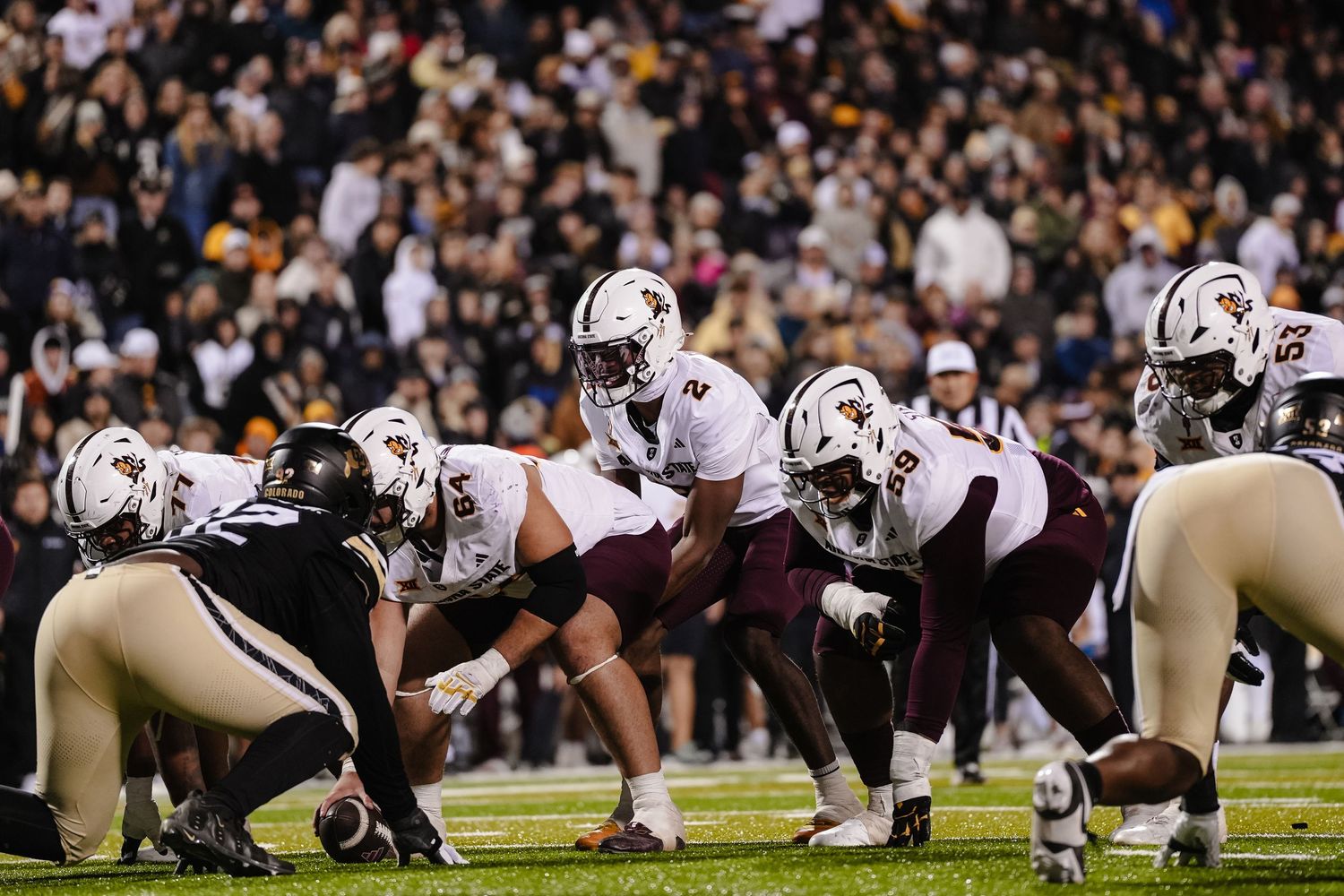 Football teams line up at scrimmage during night game.