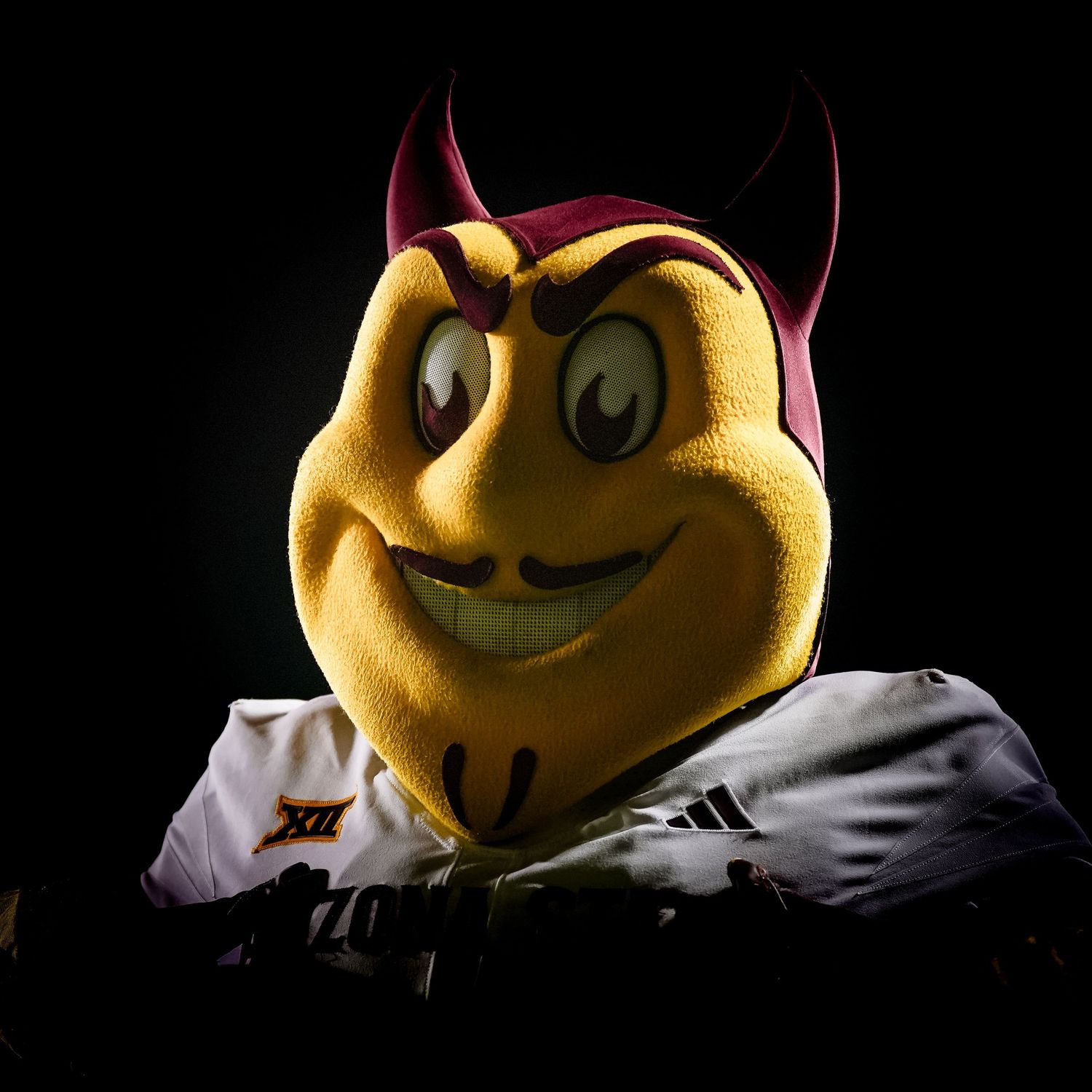 Yellow mascot head with horns photographed against dark background.