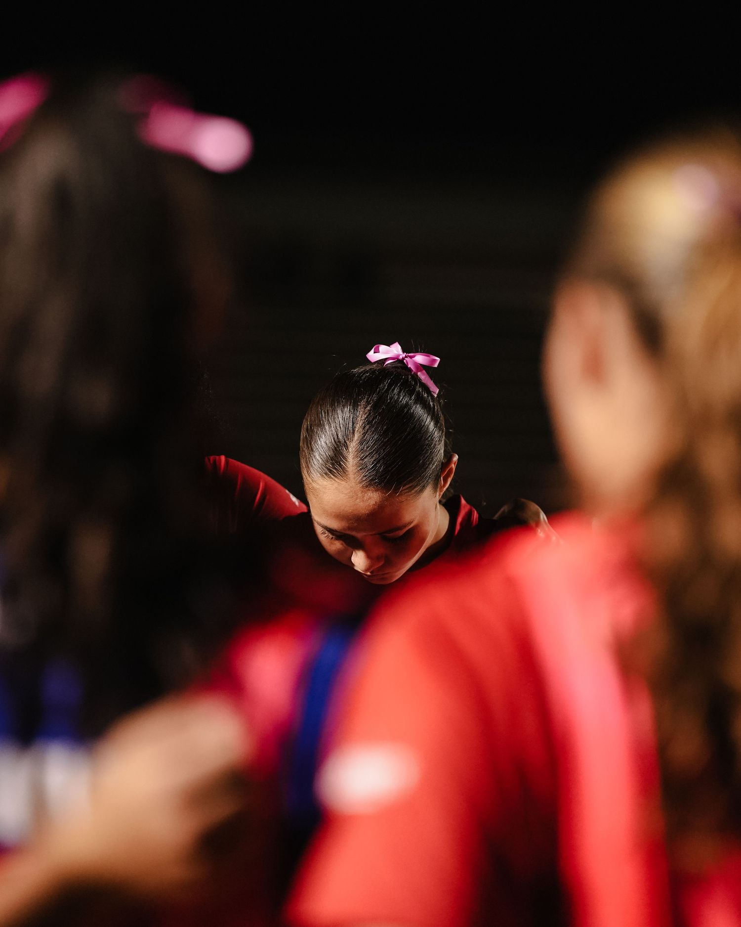 Close-up view of athletes wearing red uniforms during a nighttime sports event.