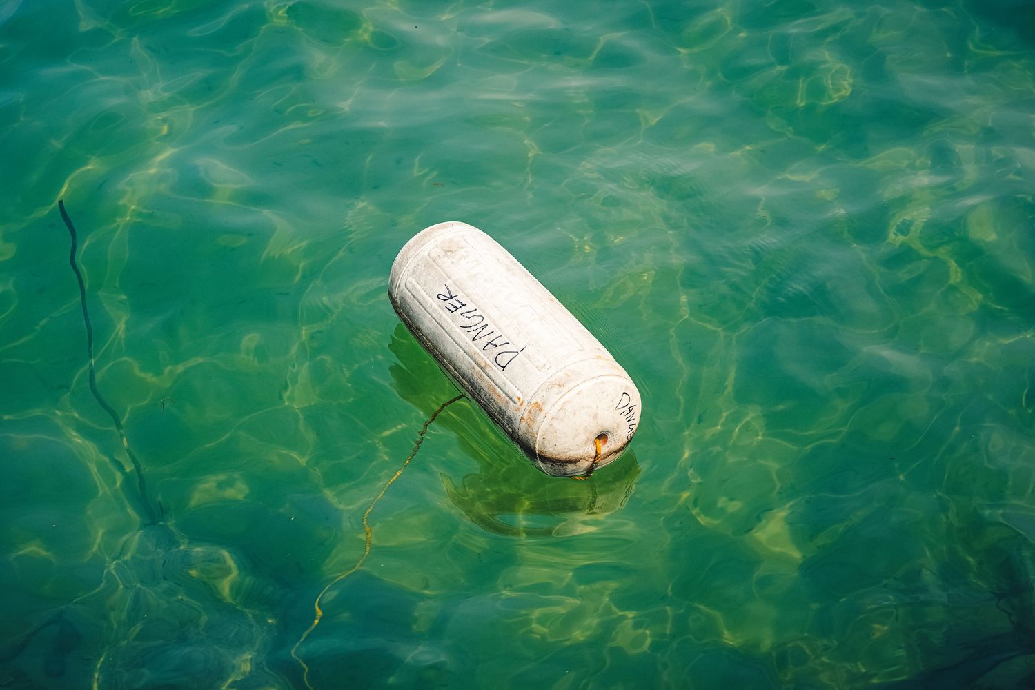 White buoy floating in rippling turquoise water.