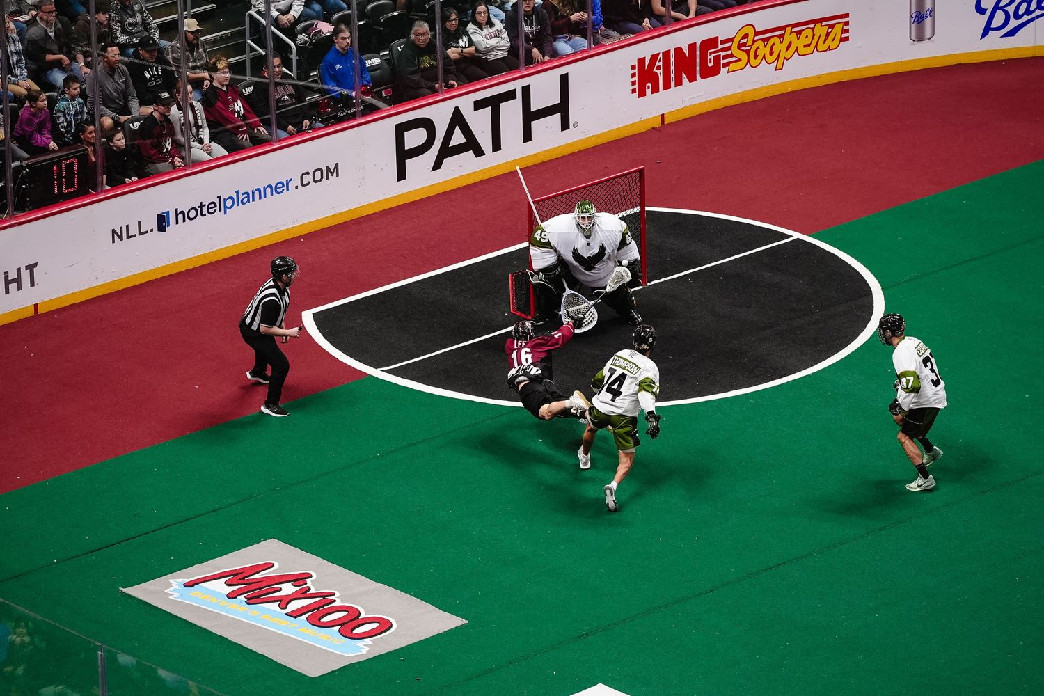 Lacrosse player dives in an attempt to score.
