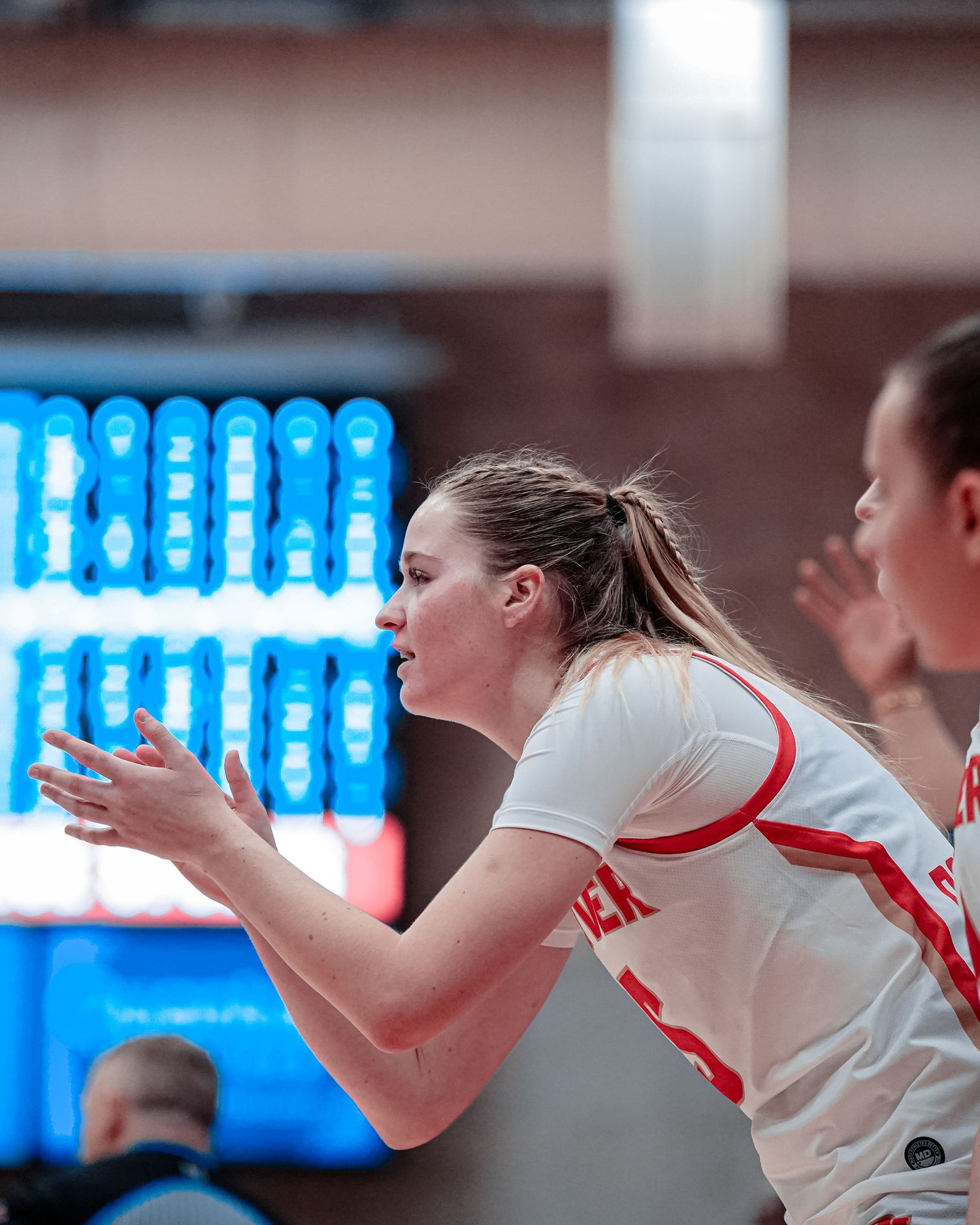 Basketball player in white and red uniform cheers from the sidelines.