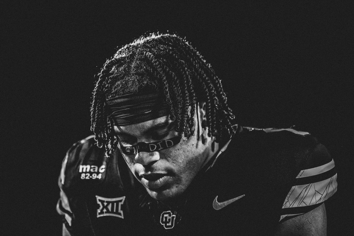 Dark atmospheric portrait of football player in uniform with dreadlocks.