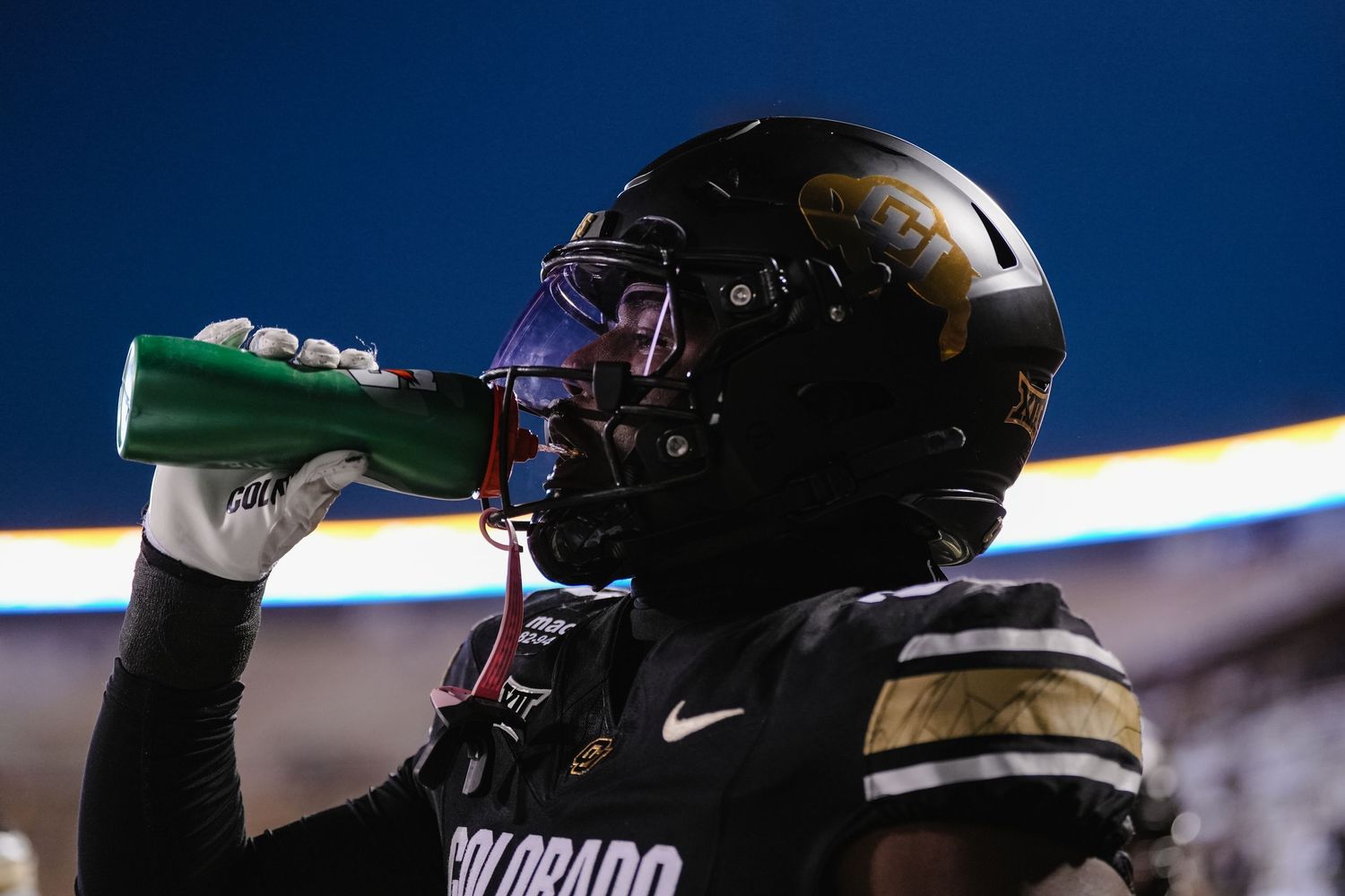 Silhouetted football player drinking water.