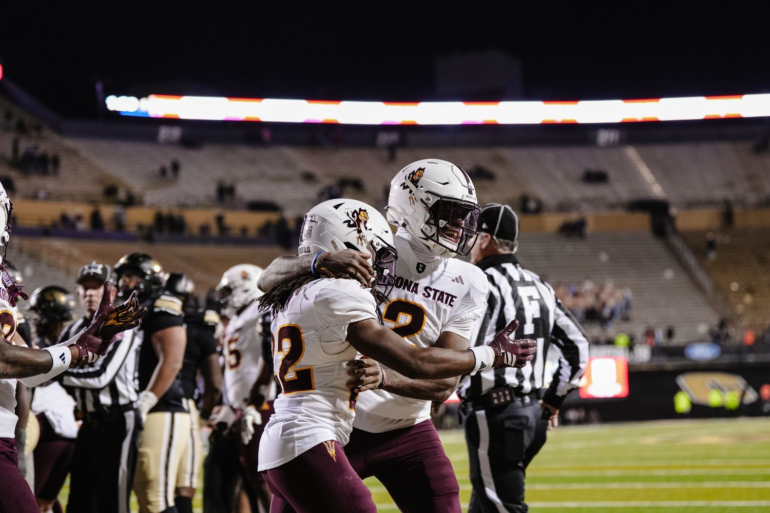 Football players celebrate touchdown in nighttime stadium game.