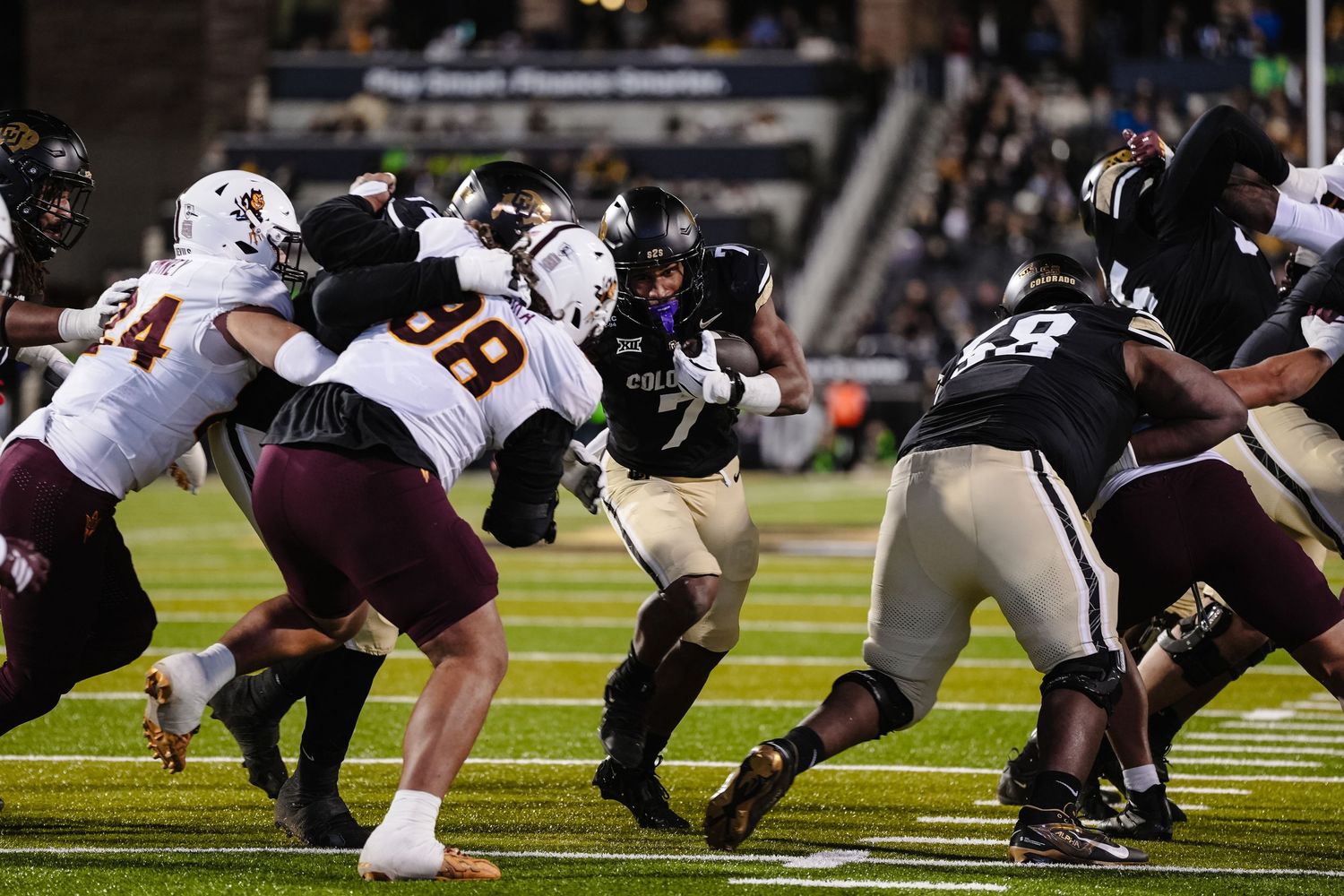Football players clash during intense play at night game.