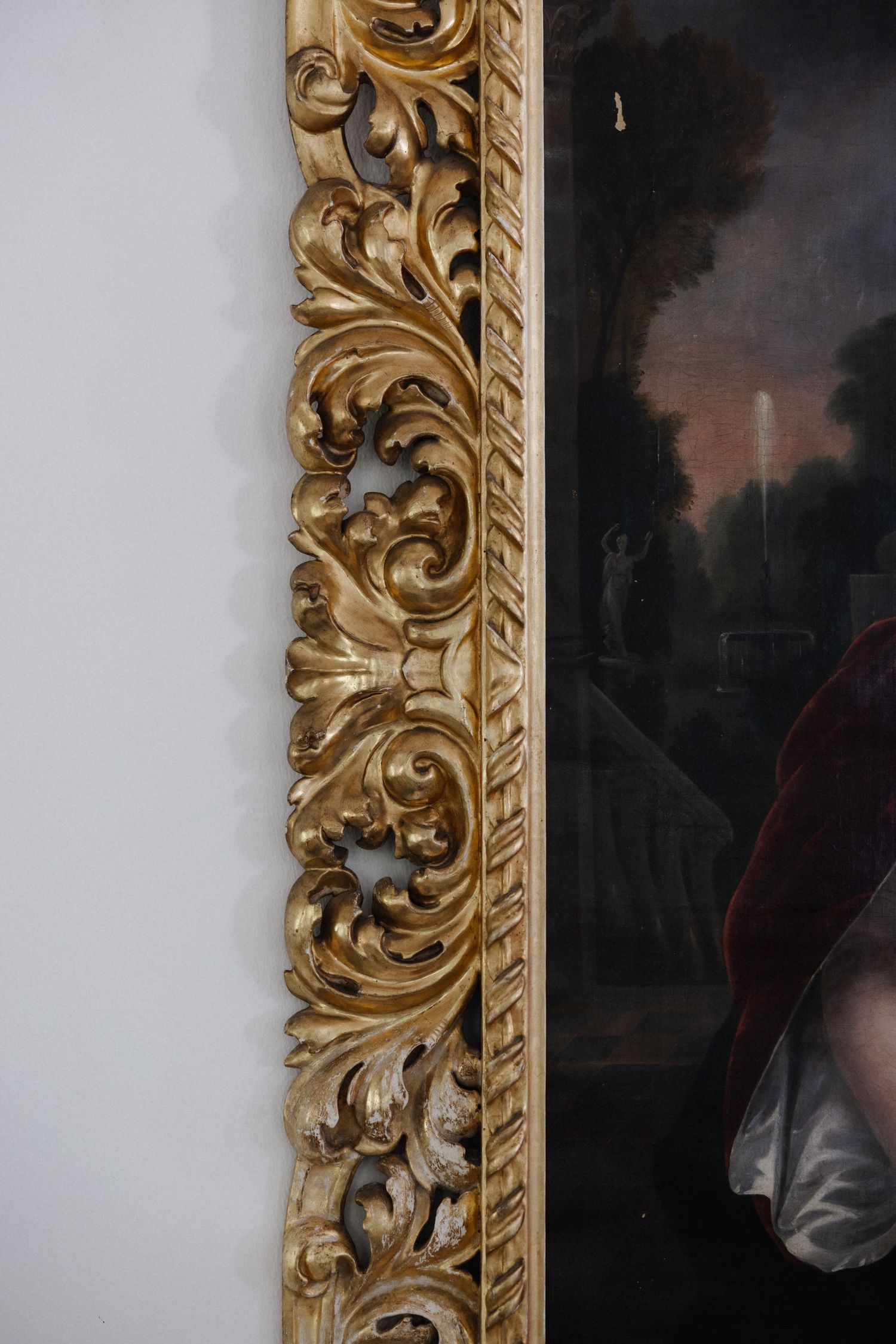 Close-up of an ornate gilded baroque picture frame with intricate carved acanthus leaf details.