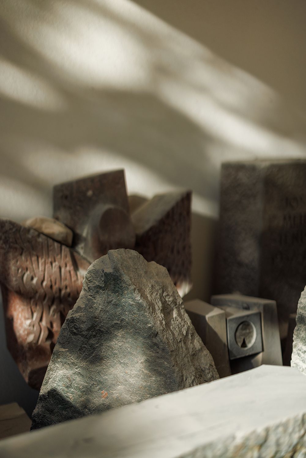 Close-up of rough textured stone blocks and carved rock fragments on a shelf in a sculptor's workshop.