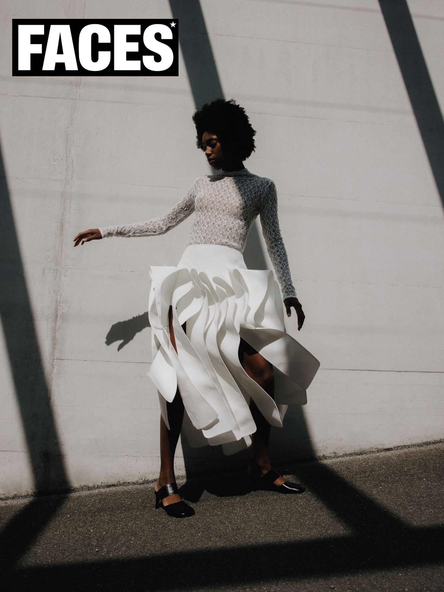 FACES magazine cover featuring Black model in white sculptural skirt and sheer top with dramatic shadows outdoors.