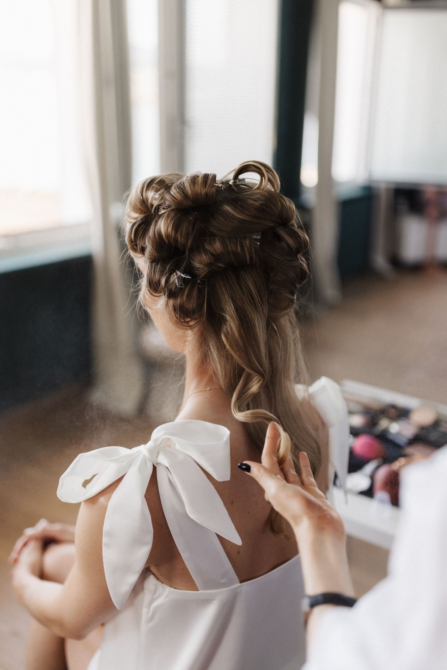 Elegant bridal updo with braids and curls being styled by hairdresser.