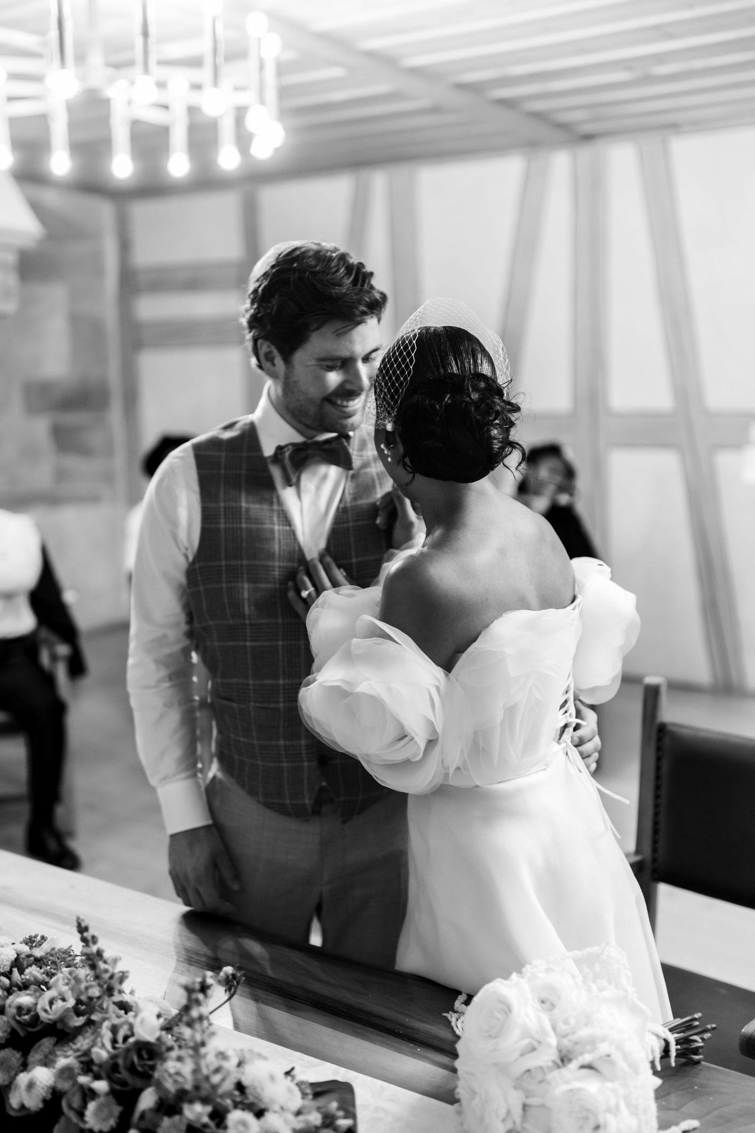 Black and white photo of interracial couple sharing intimate moment at wedding ceremony altar.