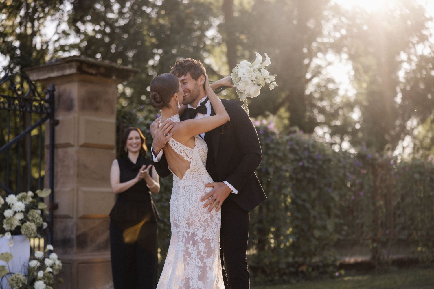 Newlyweds share their first kiss as bride and groom embrace after outdoor wedding ceremony.