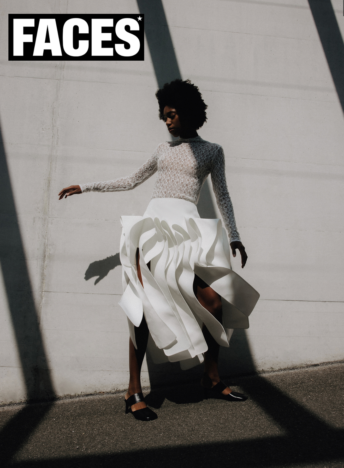 Model in white ruffled skirt and lace top posing in urban shadows, Faces magazine.