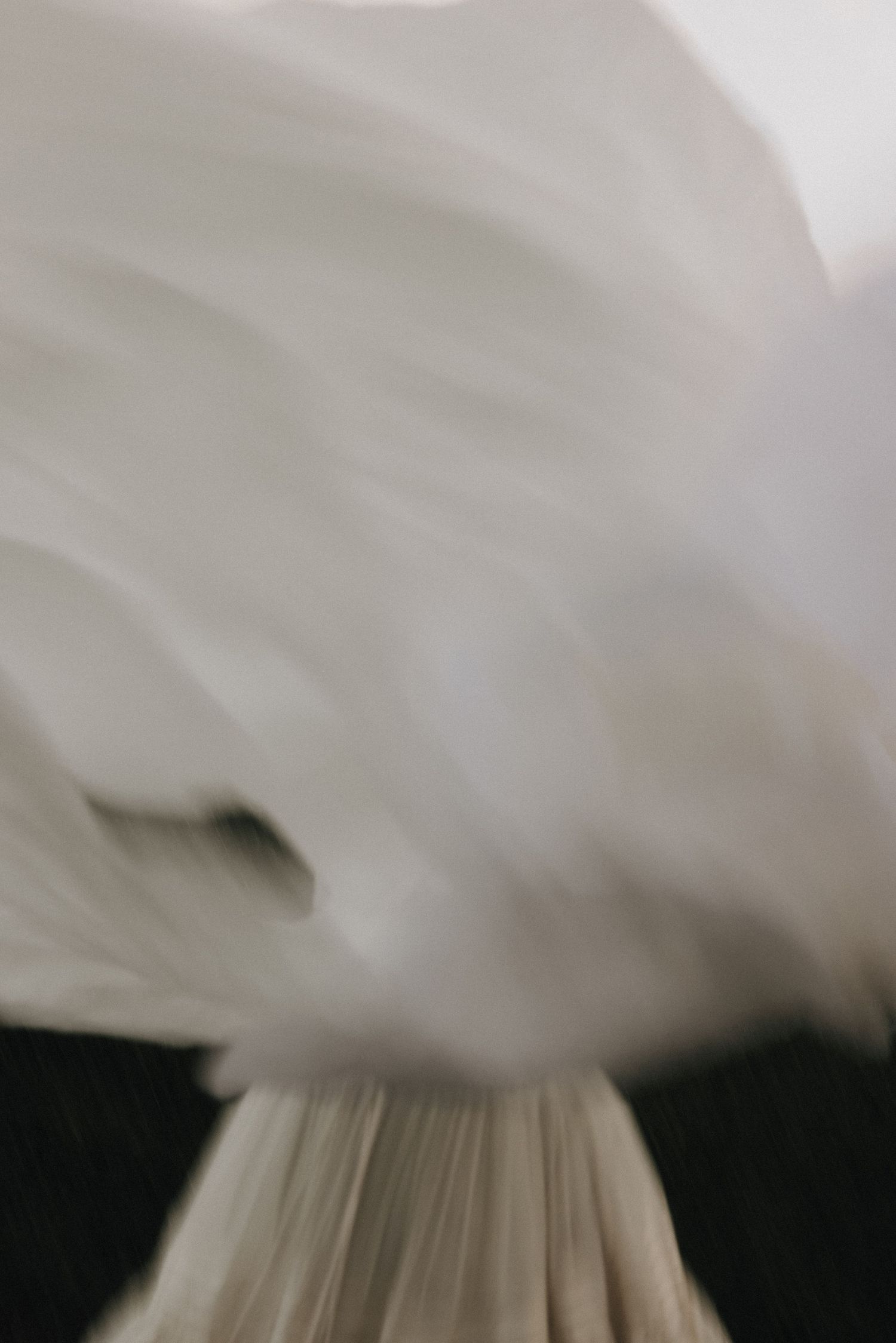 Abstract close-up of flowing white fabric captured in motion with a soft blurred background.